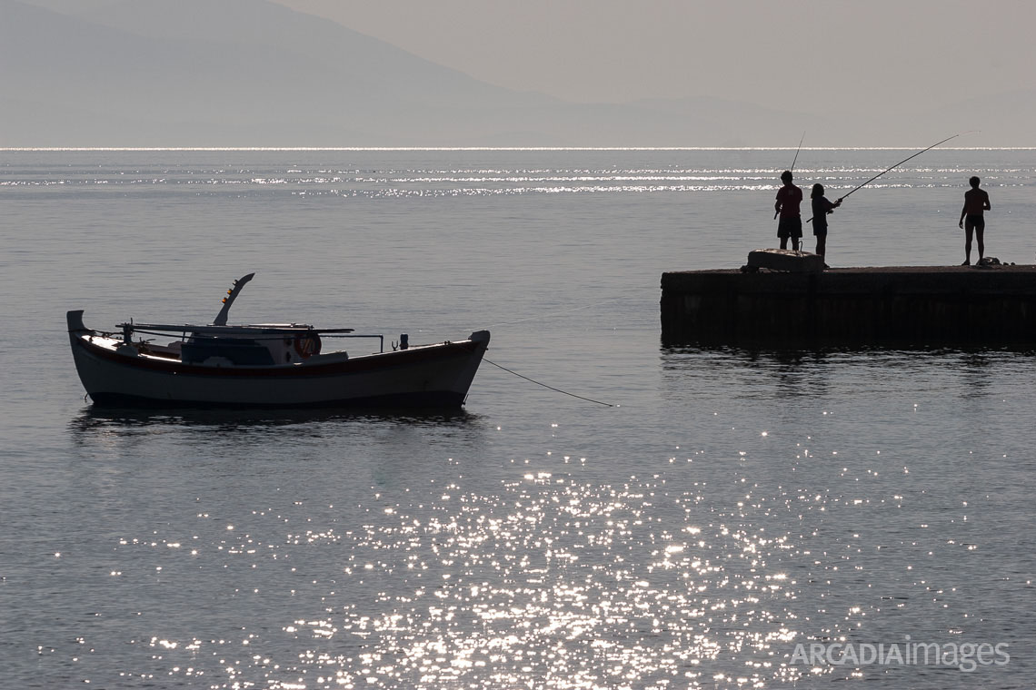 Fishermen with fishing rods standing on the jetty at Xiropigado village, Arcadia, Greece